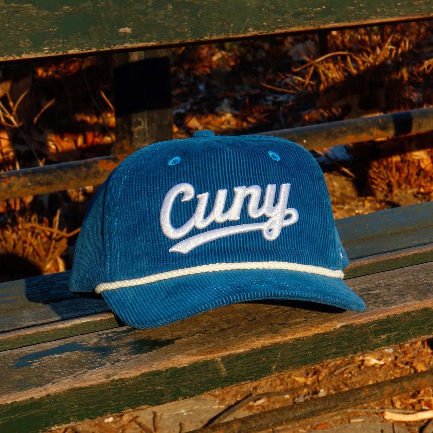 Blue cap with 'CUNY' text on a wooden bench